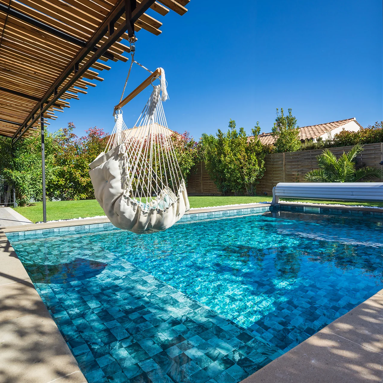 Piscine avec membrane armée BWT Be BRANE 3D Surface Tropical Jade, eau turquoise vive sous une pergola en bois avec balancelle suspendue