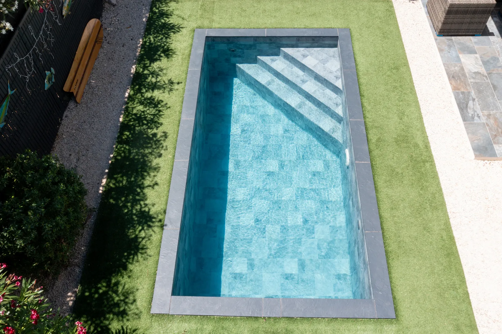 Vue aérienne d’une piscine avec membrane armée RENOLIT ALKORPLAN Ceramics Evolve Ashen, effet carrelage gris anthracite sur pelouse synthétique