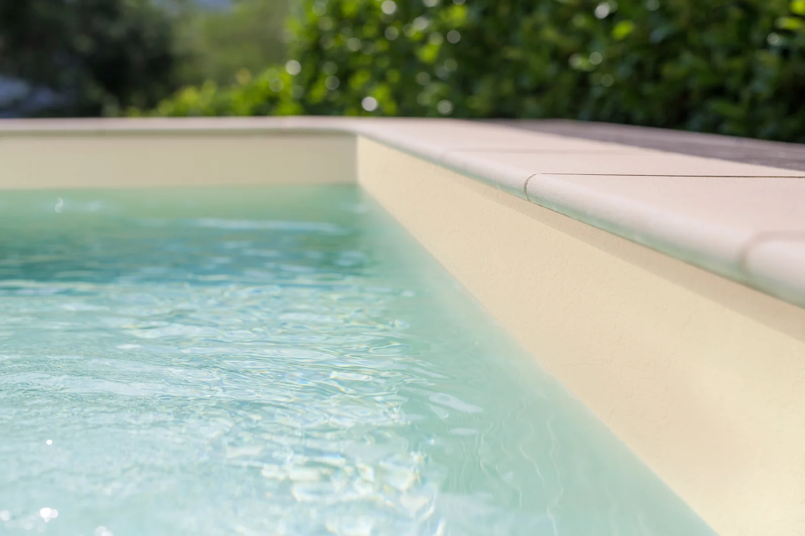Piscine avec membrane armée RENOLIT ALKORPLAN Relief Sable, paroi texturée beige et eau claire dans un jardin verdoyant