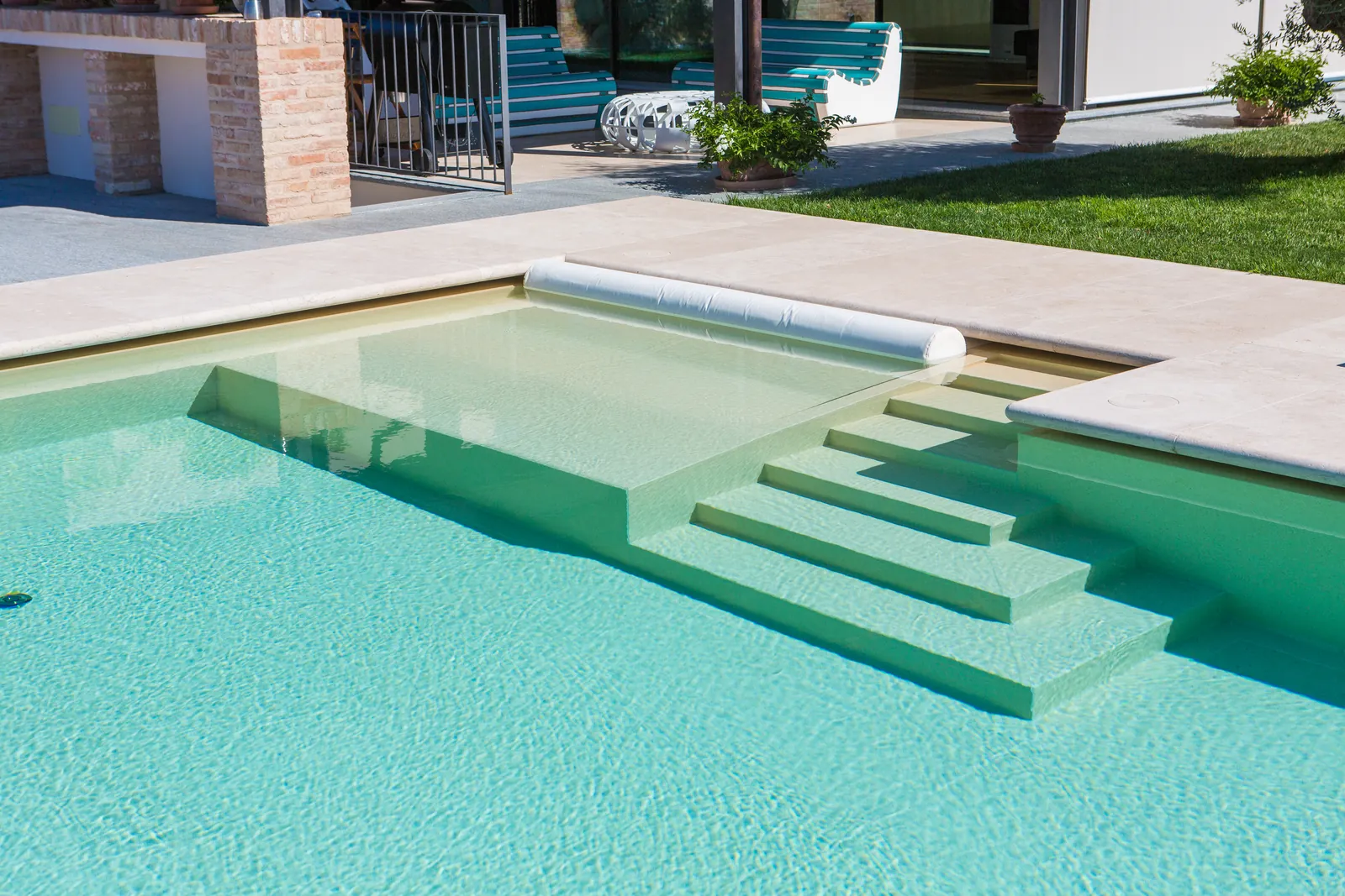 Piscine avec membrane armée RENOLIT ALKORPLAN Touch Relax, teinte sable et eau vert d’eau devant une villa avec terrasse