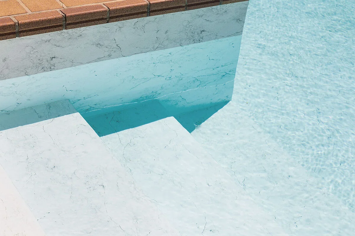 Piscine avec membrane armée RENOLIT ALKORPLAN Touch Vanity, effet marbre blanc veiné et eau claire vue sur les marches