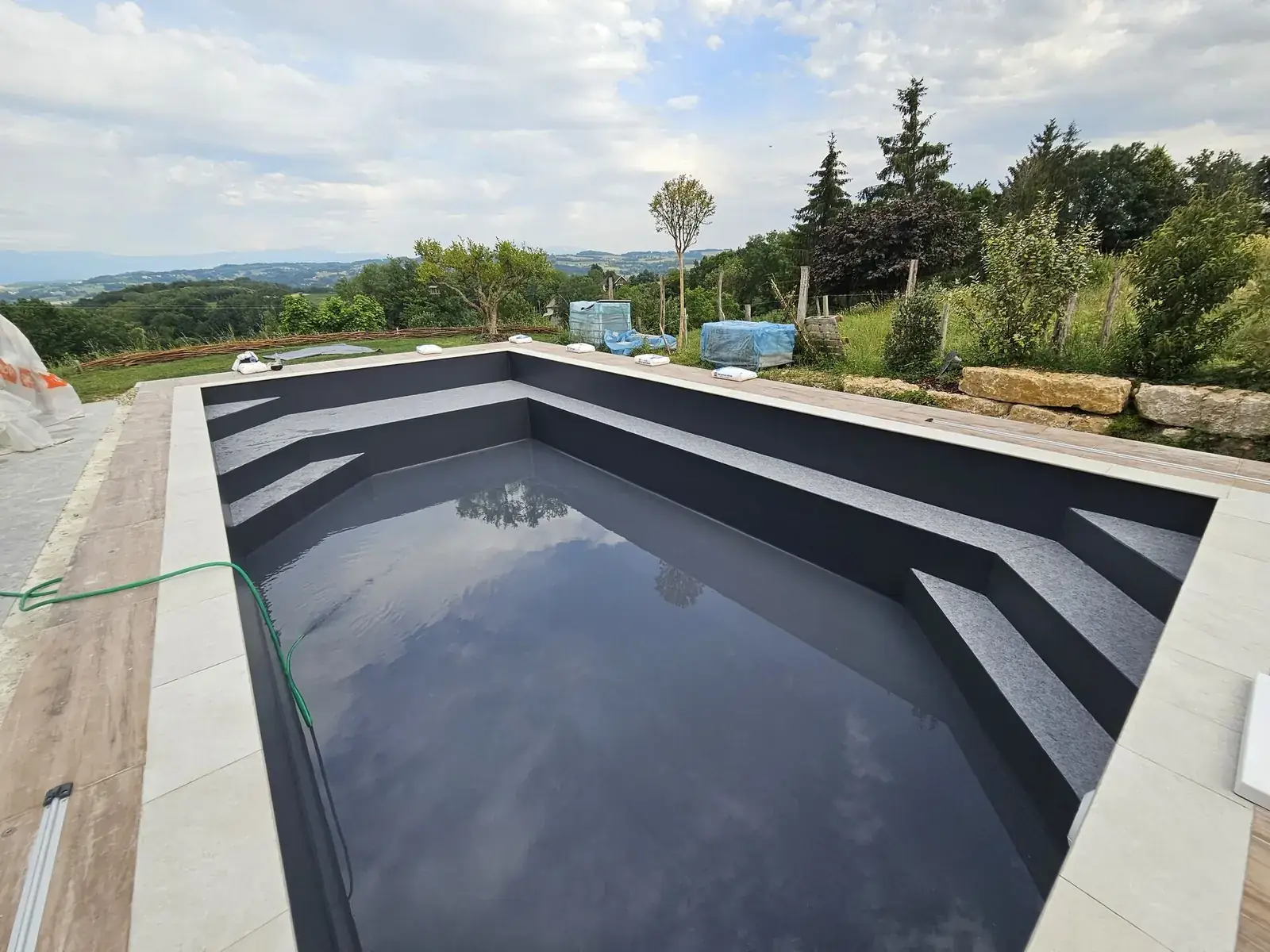 Bassin neuf avec membrane gris foncé et TOUCH Prestige sur les marches en Isère